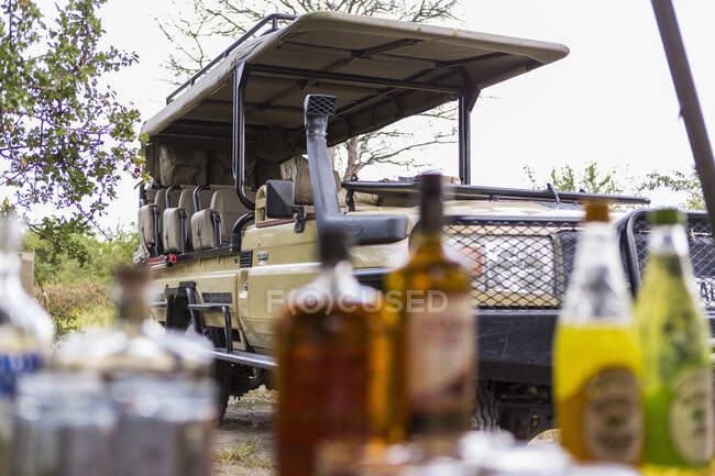 Vehículo Safari aparcado, mesa de picnic con botellas y comida . - foto de stock