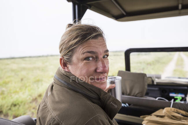 Портрет дорослої жінки на передньому сидінні сафарі-автомобіля, який дивиться над її плечем . — стокове фото