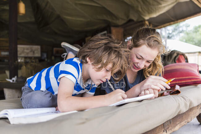Брат і сестра разом роблять домашні завдання в орендованому таборі в Ботсвані. — стокове фото