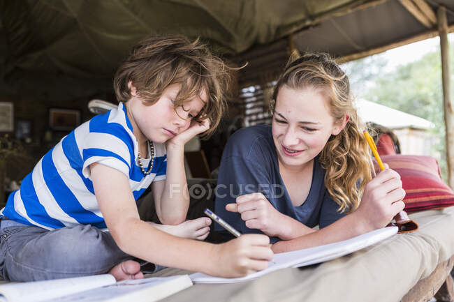 Irmão e irmã fazendo tarefas de casa juntos em um acampamento tentada no Botsuana — Fotografia de Stock