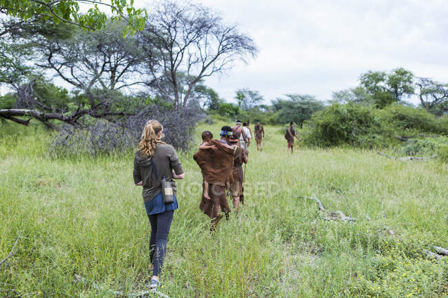 Turistas em uma trilha a pé com membros do povo San, homens do mato. — Fotografia de Stock