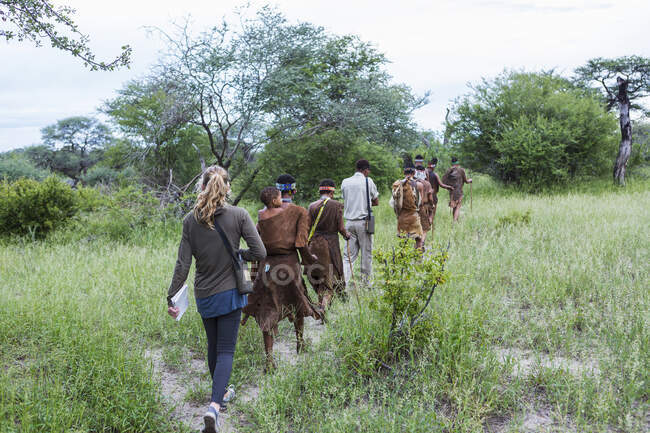 Turistas en un sendero con miembros del pueblo de San, bosquimanos. - foto de stock