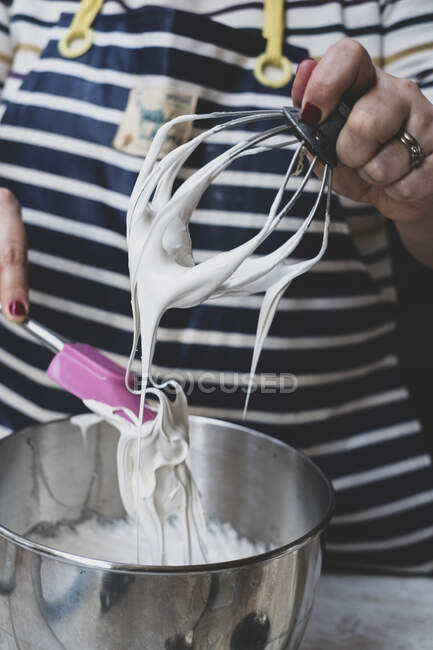 Tiro recortado de la mujer haciendo merengues batiendo claras de huevo con batidor - foto de stock