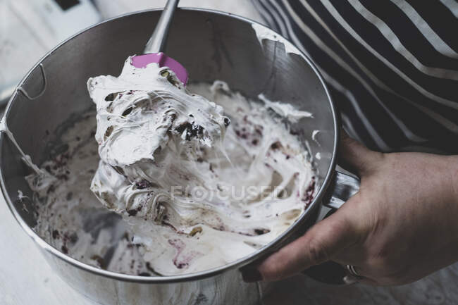 Cook folding egg whites into a baking mixture. — Stock Photo