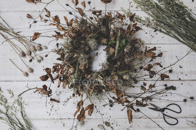 Vista superior de la corona hecha de ramitas y hojas secas, cucharaditas y cabezas de semillas - foto de stock