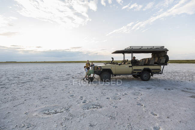 A safari vehicle parked in the salt pans landscape at dusk. — Stock Photo
