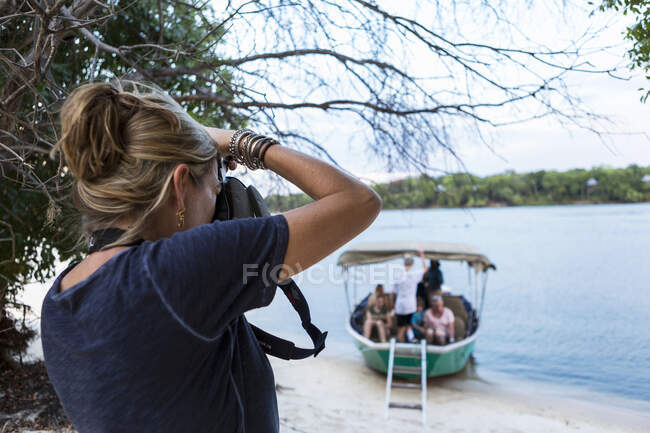 Uma mulher usando sua câmera, tirando fotos de um barco com passageiros no Rio Zambeze, Botsuana — Fotografia de Stock