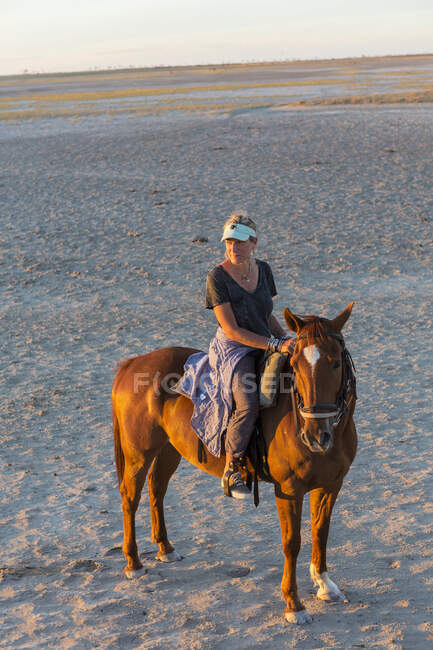 Una donna a cavallo al tramonto all'aperto. — Foto stock