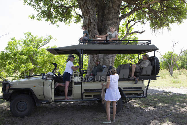 Un véhicule safari garé à l'ombre avec six membres de la famille au repos. — Photo de stock