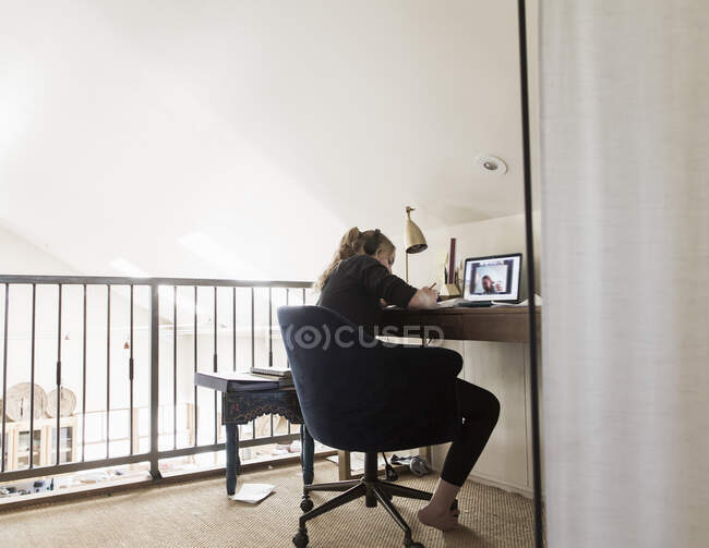 14 años de edad, chica mirando a la computadora portátil en su loft espacio - foto de stock
