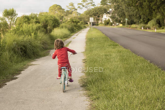 Ein fünfjähriger Junge im roten Hemd fährt mit seinem Fahrrad in einer ruhigen Wohnstraße. — Stockfoto