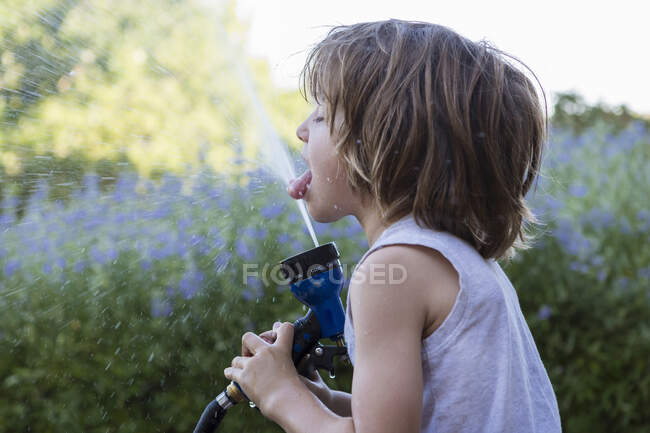 5 year old boy drinking from water hose — Stock Photo