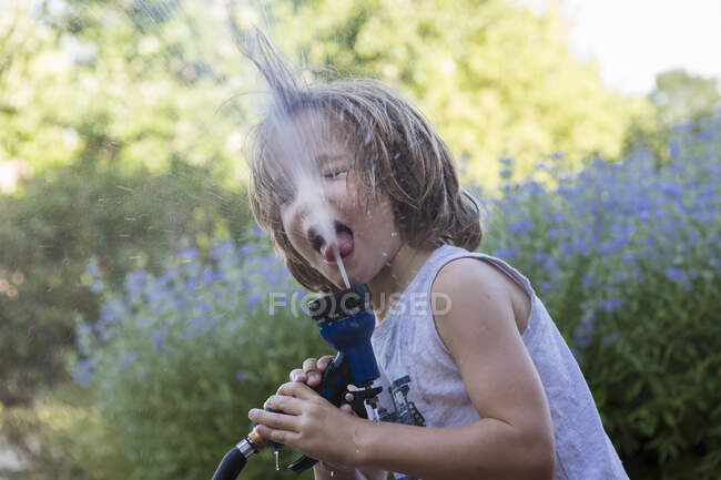 5 anos de idade menino bebendo de mangueira de água — Fotografia de Stock