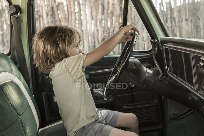 5-jähriger Junge am Steuer eines Pick-ups aus den 1970er Jahren, NM. — Stockfoto