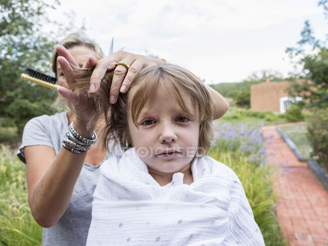 5 anos de idade menino recebendo seu cabelo cortado pela mãe fora — Fotografia de Stock