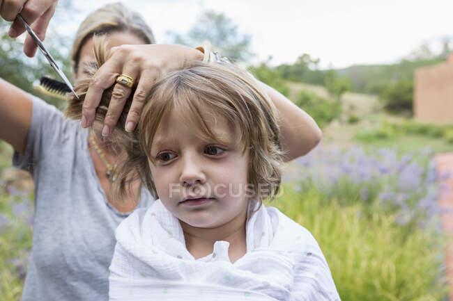 5 ans garçon obtenir ses cheveux coupés par la mère à l'extérieur — Photo de stock