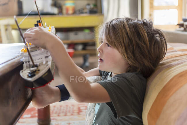 5 anno vecchio ragazzo giocare con la sua giocattolo barca a casa — Foto stock