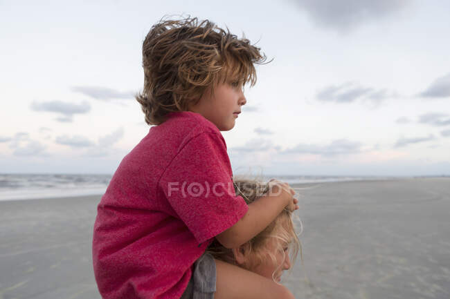 5 años de edad, hermano montar en su hermana hombros en la playa, Georgia - foto de stock