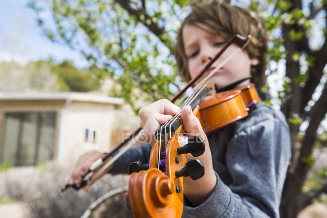 6 year old boy playing violin outside of his home — Stock Photo