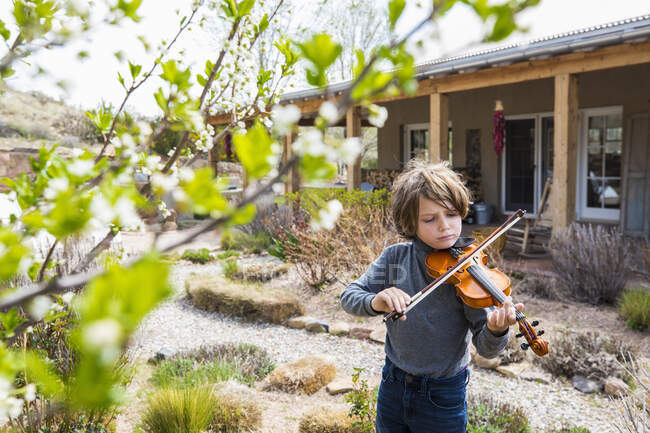 Niño de 6 años tocando el violín fuera de su casa - foto de stock