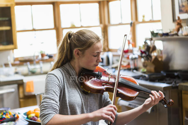 Niña de 13 años tocando el violín en casa - foto de stock