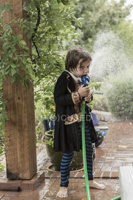 Als Pirat verkleideter kleiner Junge trinkt aus Wasserschlauch — Stockfoto