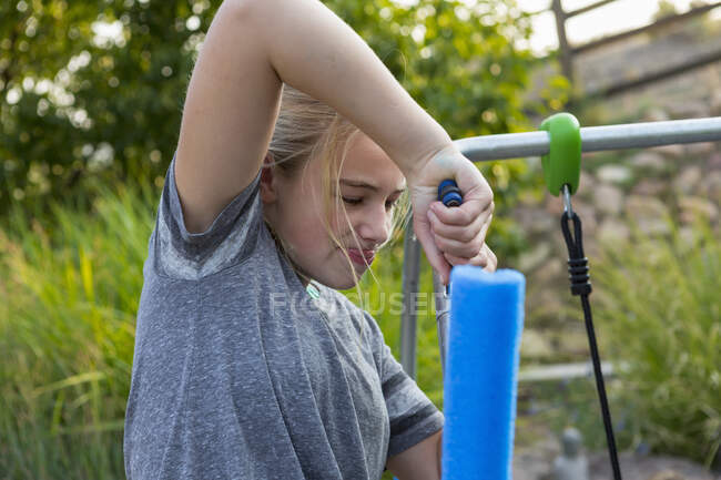 11 anno vecchio ragazza fissaggio swing in cortile — Foto stock