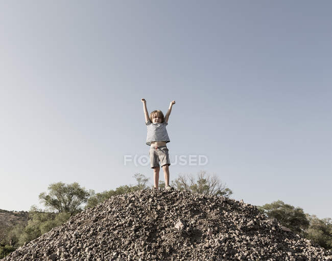 4 year old boy raising arms in triumph on top of hill — Stock Photo