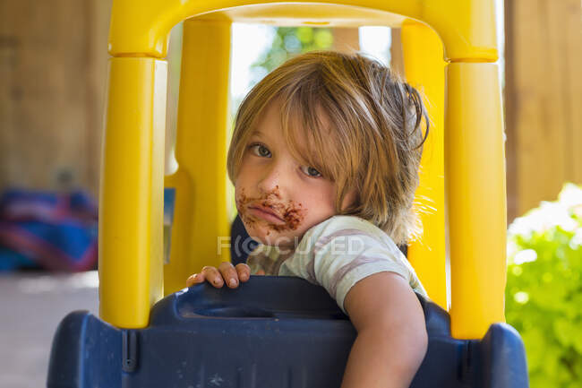Портрет улыбающегося 4-летнего мальчика с шоколадом на лице, играющего и смеющегося — стоковое фото