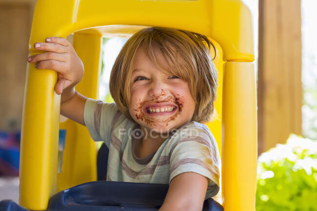 Portrait of smiling 4 year old boy with chocolate on his face playing and laughing — Stock Photo