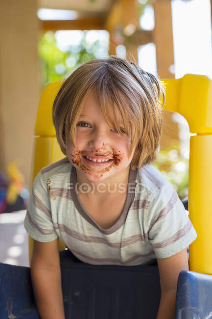 Ritratto del ragazzo sorridente di 4 anni con il cioccolato sul viso che gioca e ride — Foto stock