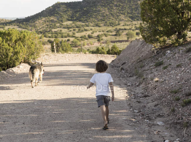 Niño de cuatro años haciendo senderismo en un paisaje rural - foto de stock