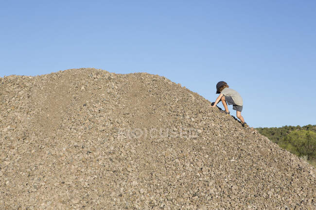 Menino de 4 anos escalando uma colina de cascalho — Fotografia de Stock