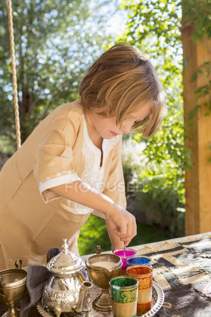 4 year old boy using colored water for eggs, Easter — Stock Photo
