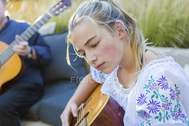 Vista de cerca de la chica adolescente enfocada tocando la guitarra al aire libre - foto de stock