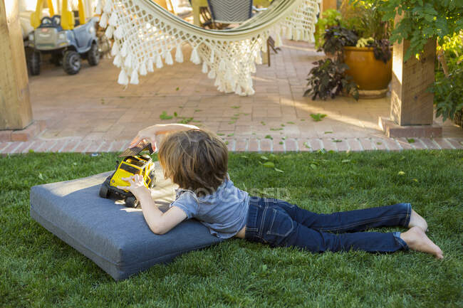4 year old boy playing with a toy on green lawn — Stock Photo