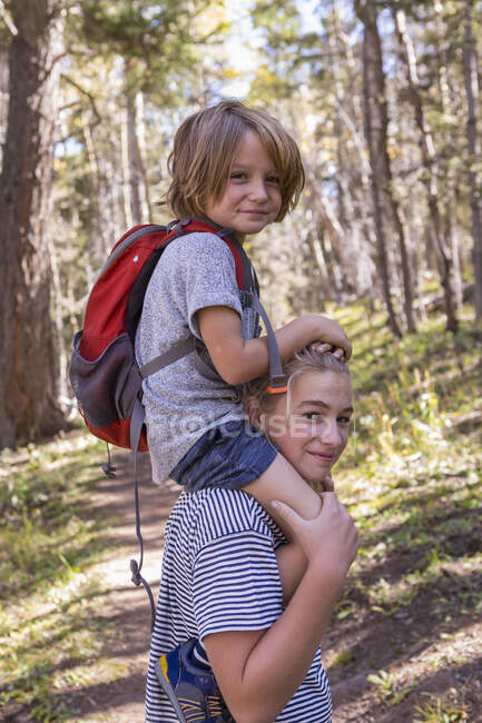 4 año viejo chico consiguiendo paseo en hermana hombros - foto de stock