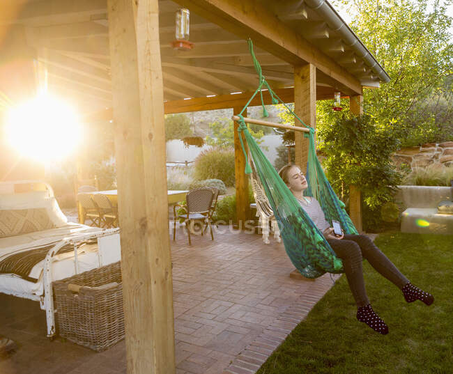 11 anos de idade menina balançando em rede ao pôr do sol — Fotografia de Stock