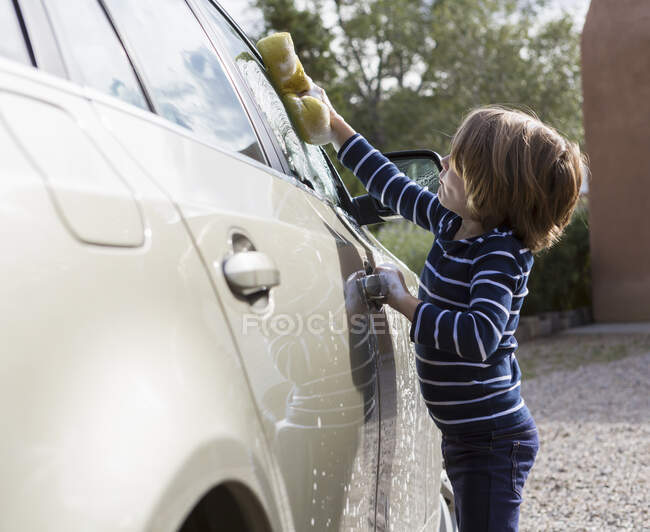 Vierjähriger Junge wäscht Auto auf dem Parkplatz — Stockfoto