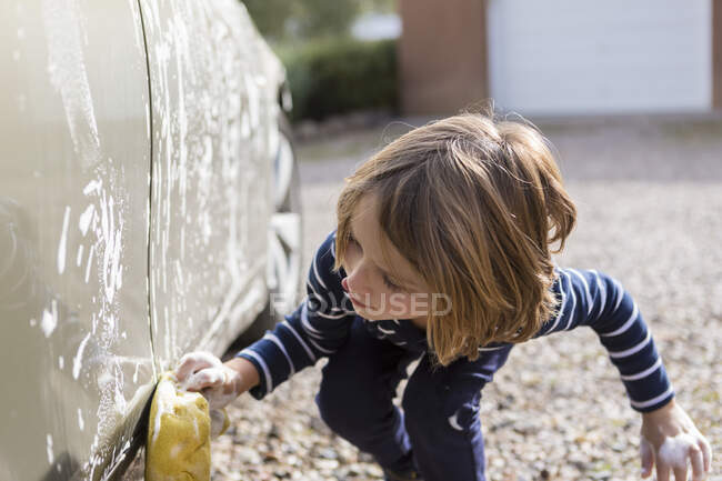 Garçon de 4 ans laver une voiture dans le parking — Photo de stock