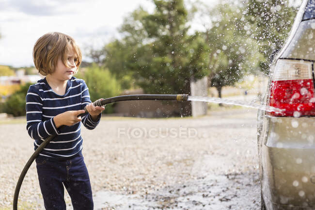 Garçon de 4 ans laver une voiture dans le parking — Photo de stock