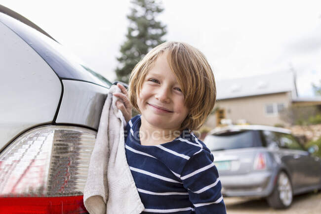 4 year old boy washing a car in the parking lot — Stock Photo