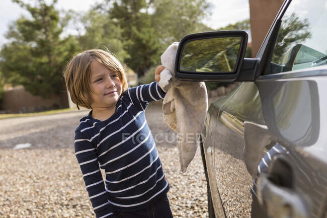 Quatro anos de idade menino polir um carro exterior com mais limpo e um pano — Fotografia de Stock