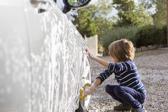 Ragazzo di quattro anni che lava un'auto con un detergente e un panno — Foto stock