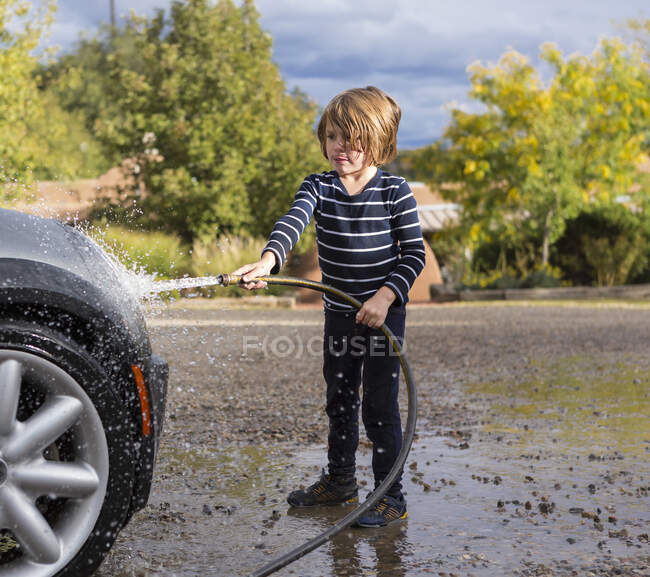 Vierjähriger Junge wäscht Auto mit Schlauch — Stockfoto
