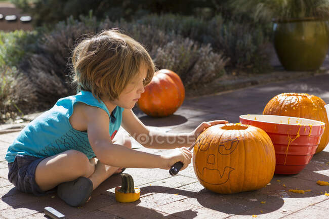 Garçon de 4 ans sculptant une citrouille — Photo de stock