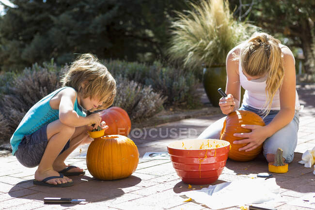 Мальчик и его сестра вырезают тыквы — стоковое фото