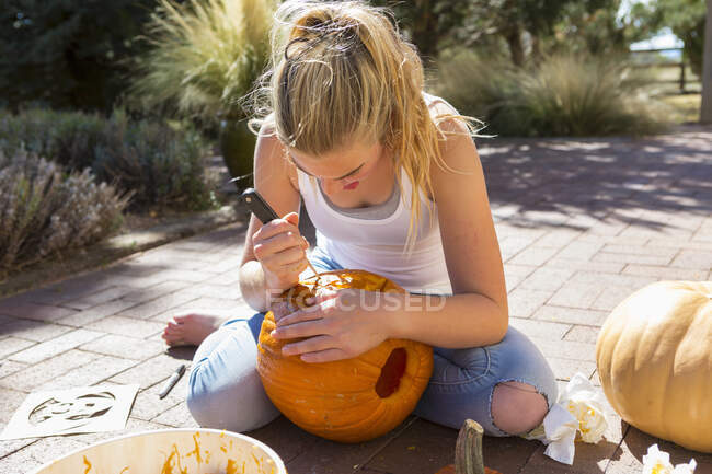 11 anno vecchio ragazza carving un zucca — Foto stock