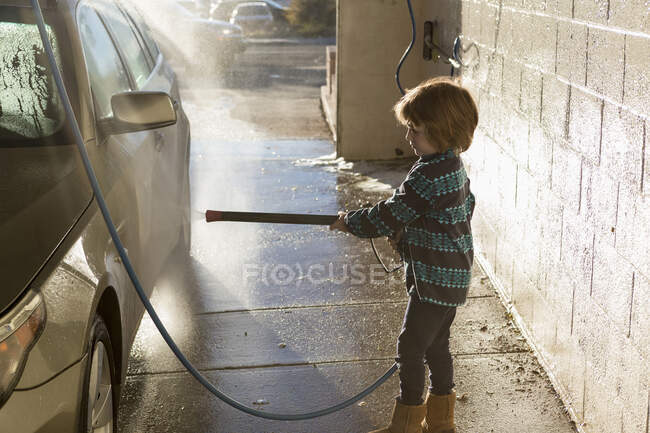 4 ans garçon laver une voiture dans le lavage de voiture — Photo de stock