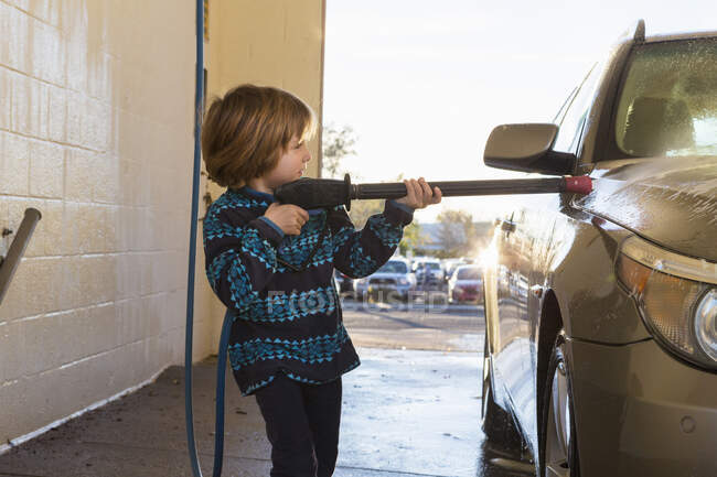 4 anno vecchio ragazzo lavaggio un auto in auto lavaggio — Foto stock